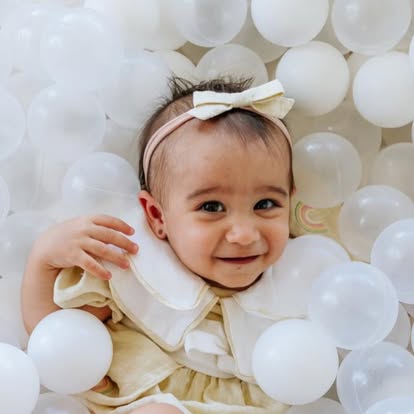 Bebê sorrindo em piscina de bolinhas branca da Baluê
