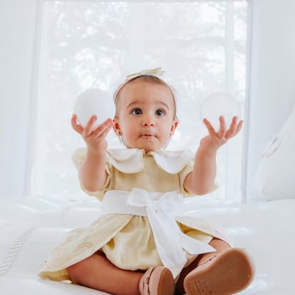 Bebê brincando com bolas brancas dentro de um castelo inflável da Baluê
