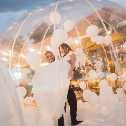 Pai e criança brincando em uma bolha transparente montada pela Baluê em casamento