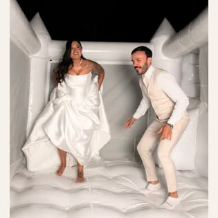 Casal em um castelo inflável branco da Baluê durante uma celebração